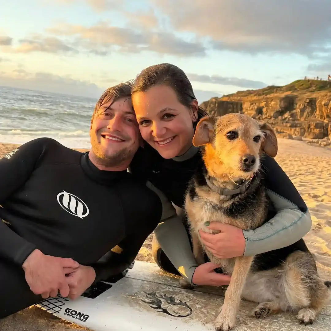 Paar mit Hund und Surfboard am Strand in Portugal, Freunde von LAR Baumwolldecken