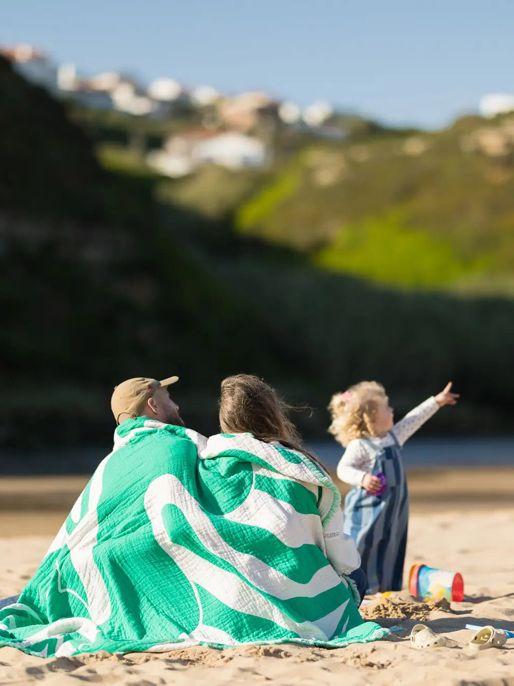 Familie mit grüner Kuscheldecke von LAR am Strand in Portugal