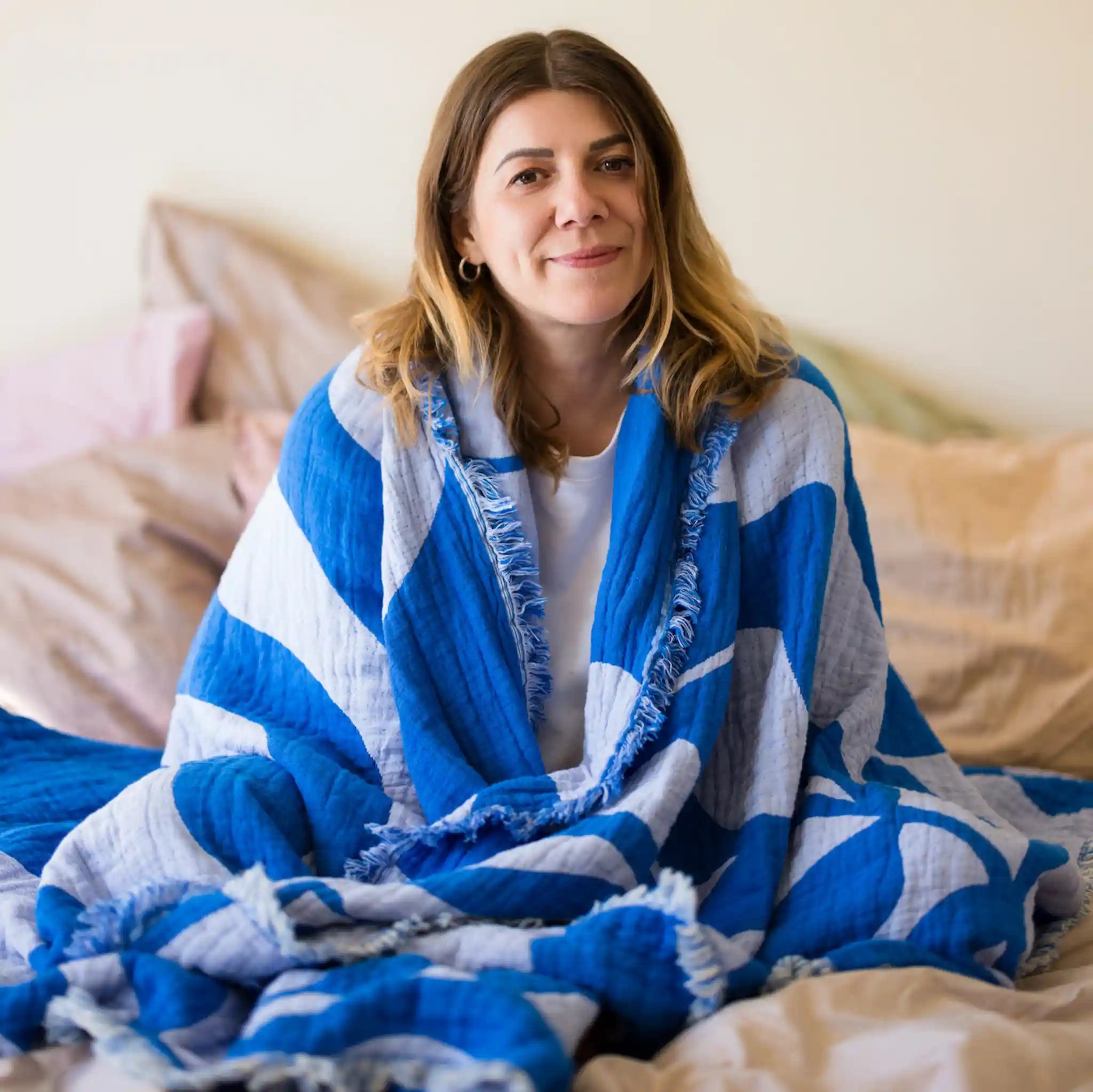 Gründerin von LAR im Bett mit blauer LAR Decke